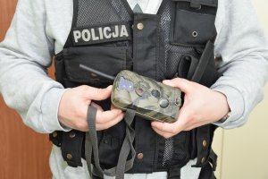 Policjant prezentuje zabezpieczoną fotopułapkę